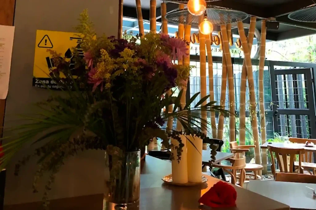 The interior of the Cofy Club restaurant, featuring fresh flowers, warm lighting, and bamboo decor in El Poblado.