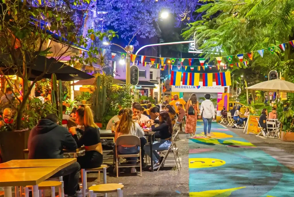 Calle de El Poblado Medellín de noche con banderas del Mundial 2026 y ambiente festivo