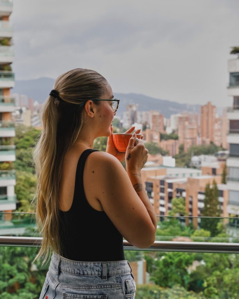 Huésped tomando café en terraza con vista al skyline de Medellín