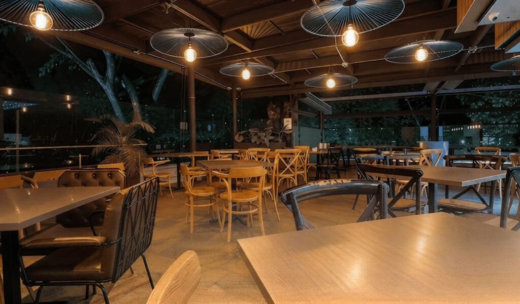 Cofy Club restaurante de Café Hotel con mesas y luz cálida en la noche.